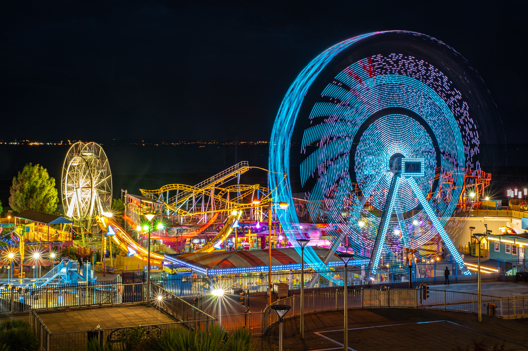Adventure Island illuminated at night on Southend-on-Sea seafront, with fairground rides and the Thames Estuary beyond.